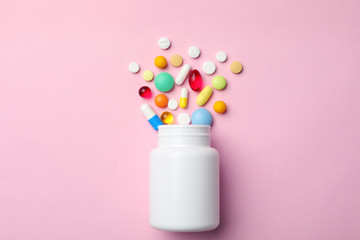 Bottle with different pills on color background, flat lay