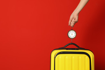 Woman weighing suitcase against color background, closeup. Space for text