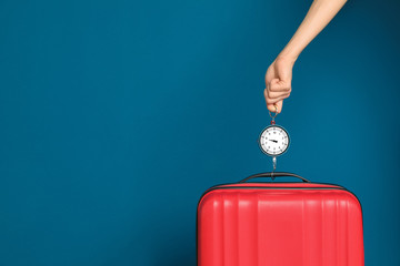 Woman weighing suitcase against color background, closeup. Space for text