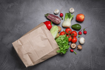 paper package with fresh vegetables and fruits on dark background, flat lay