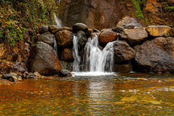 Fantastic landscape  view of waterfall flowing around rocks with greens and stones in long exposure.