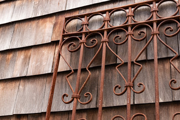 Weathered wood shingle siding and rusty wrought iron metal gate