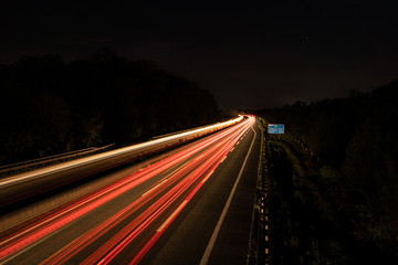 Fototapeta na wymiar Langzeitbelichtung auf der Autobahn. Nachtlichter, Stadtlichter, Geschwindigkeit, Transport, Traffic, Autos in Bewegung, Fahrbahn, Road