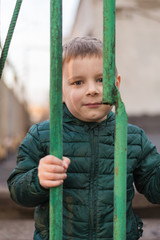 The child is behind bars. A little boy is behind a metal fence.