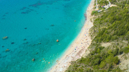Fototapeta na wymiar AERIAL: Flying above colorful deckchairs and umbrellas on the secluded beach.