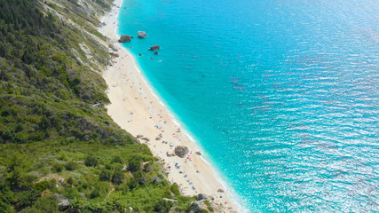AERIAL: Stunning view from above of a remote white sand beach and turquoise sea.