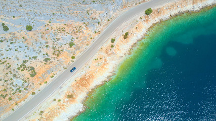 AERIAL: People cruising along the stunning shoreline of Lefkada in a grey car.