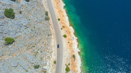 DRONE: Tourist car drives along the glistening ocean on a perfect summer day.