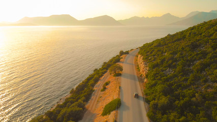 AERIAL: Beautiful shot of Mediterranean nature and sea surrounding car cruising.