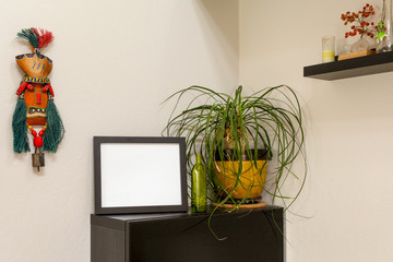 Blank black horizontal picture frame on a shelf with a ponytail palm  and a tribal mask. For mocking up photos and artwork.