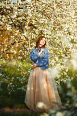 Portrait of a beautiful bride. Wedding concept. Stylish wedding. Great sunset light. She is wearing a blue denim jacket, dress. Spring blooming garden.