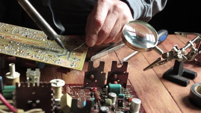 master soldering radio components on the desktop, close-up