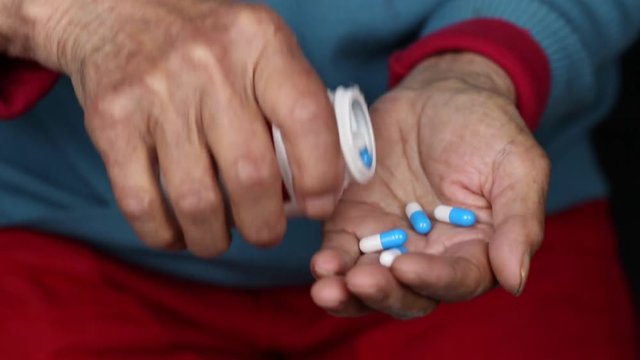 Close up of Chinese elderly female taking pills out of medicine box
