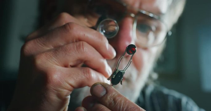 Slow motion close up of experienced goldsmith controlling a quality of rubin stone, selected for making jewels in workshop.Shot in 8K. Concept of jewelry,luxury,goldsmith, diamonds, brilliance.