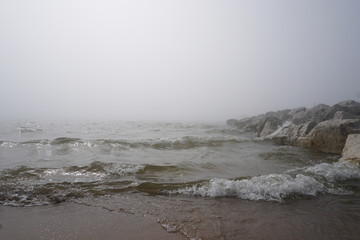 beach with in fog with rocks and waves