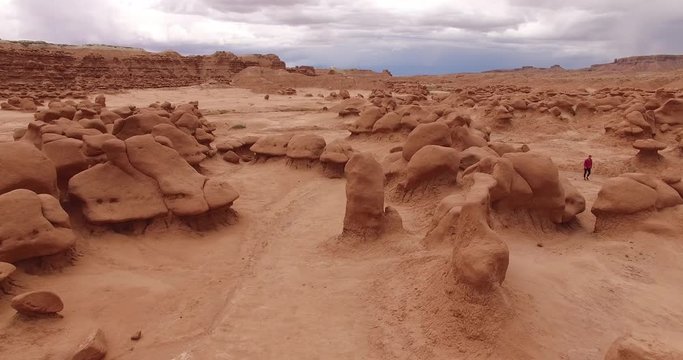 GOBLIN VALLEY STATE PARK, UTAH, USA. Lonely tourist walking along the desert trail. Man in colorful clothes walks among the nooks and gnomes.