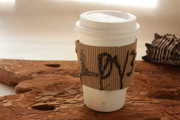 Love coffee paper cup surrounded by corrugated cardboard next to the window with rustic style wood and a snail
