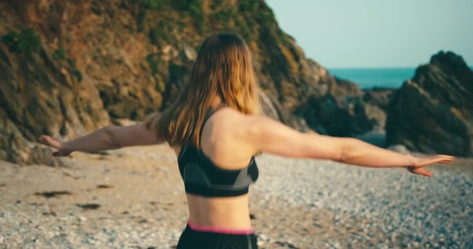 Fitness woman warming uyp for beach workout at sunset