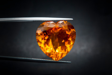 Natural madeira citrine Gems Stone oval cut beautiful.Holding a yellow stone by tweezers.