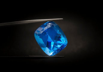 Natural Swiss Blue Topaz Cushion Shape Gems Stone oval cut beautiful.Holding a blue stone by tweezers.
