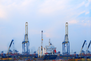Obraz premium Small boats in the harbor, and cranes lifting containers