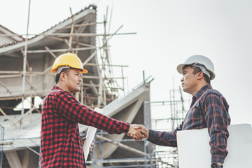 Two male engineer industry stands shake hands with the team and construction contract business
