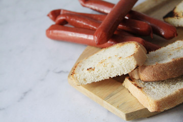 Grilled sausages and bread on a wooden Board on a marble table