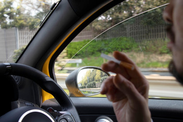 車を運転しながらタバコを吸う男性