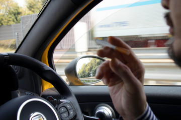 車を運転しながらタバコを吸う男性