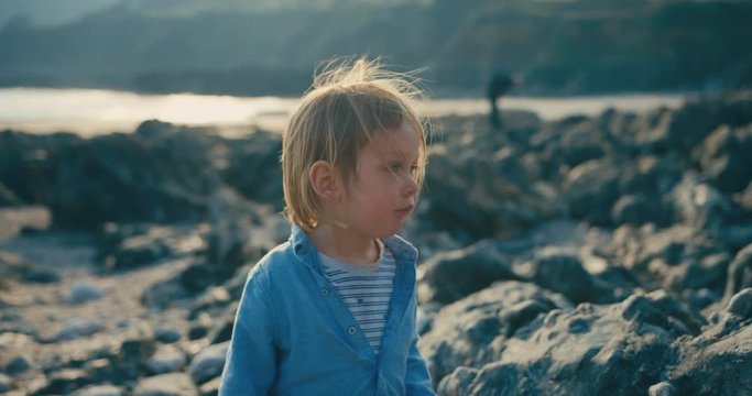 Little toddler standing on the beach at sunset