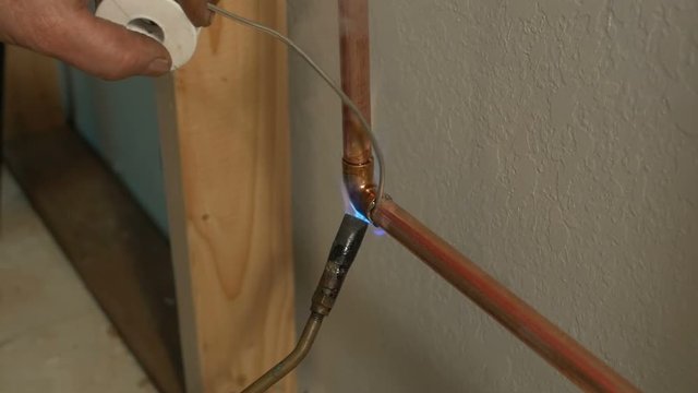A plumber soldering pipes on a home remodel project