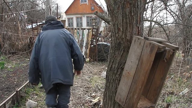 The poor old grandfather walks through the patch of land to the rickety gate and the old collapsed house. Life in an abandoned village.