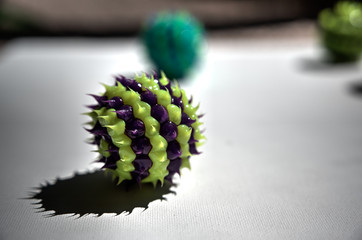 purple and green striped ball with spikes on white surface