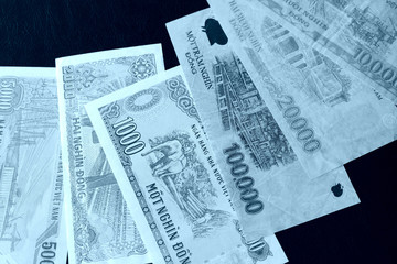 Vietnamese dongs on a dark background close up. Blue color toned