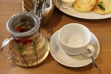 Teapot and Cup of tea inside on wooden background in cafe on table