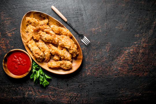 Chicken Strips On A Plate With Greens And Sauce.