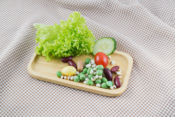 Cereal Grains and fresh vegetable on Wood tray and plaid cloth background, selective focus (detailed close-up shot)