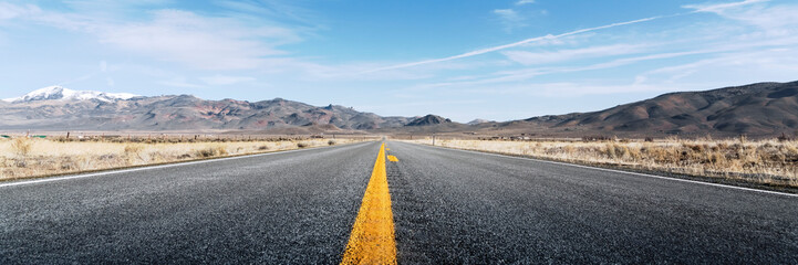 Long straight road through desert, empty street leading into horizon, two lanes asphalt route