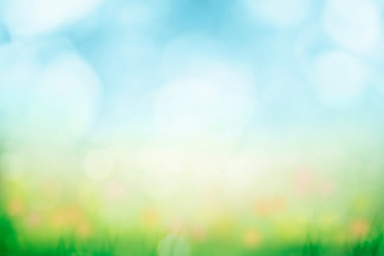 Abstract background with green grass and flowers over sunny blue sky