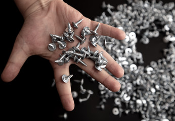 Sharp screws in hand on black background