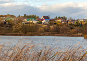 Fototapeta na wymiar Cottage village on the shore of the pond in autumn