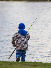 The boy catches fish on the pond at sunset