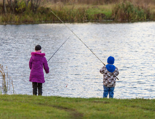 The boy with the girl catches fish in the pond at sunset