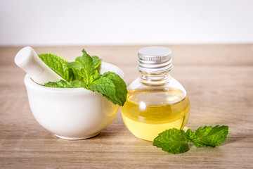 Aroma essential oil from a peppermint in the bottle on the table with fresh green mint leaf © Cozine