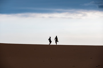 Fototapeta na wymiar the contour of people in sand desert in sunrise