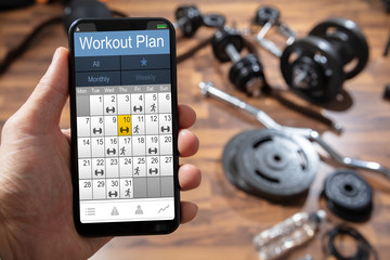 Person' Hand Holding Workout Plan On Cellphone
