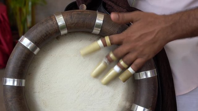 Indian man an playing on a Bongo drum during religious ceremony in Sri Mariamman Hindu Temple in Chinatown, Singapore, Southeast Asia, close up
