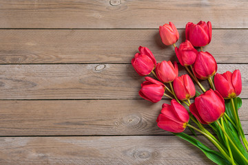 Row of red tulips on wooden background with space for text, message. Mother's Day, Hello spring concept. Card. Flat lay. Top view. Rustic style. 