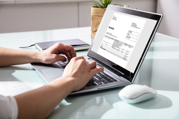 Businesswoman Checking Invoice On Laptop