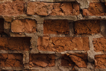 The wall of red dilapidated brick. The ruined brick wall close-up. Facade of a destroyed brick building. Pattern, texture, background.